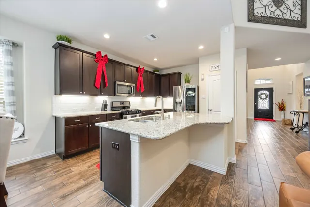 a kitchen with stainless steel appliances granite countertop a sink dishwasher stove and refrigerator with wooden floor