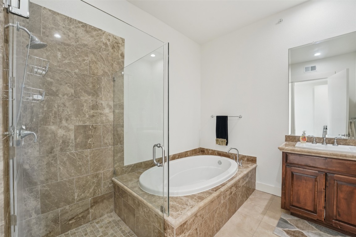 1101 Ivean Pearson Road, Unit E203 Lago Vista, TX 78645 - Photo 22 of 29 a bathroom with a tub a sink a mirror and a shower