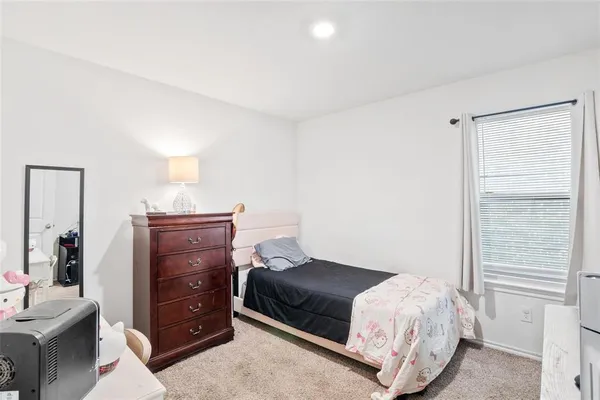 a bedroom with a bed a flat screen tv and dresser