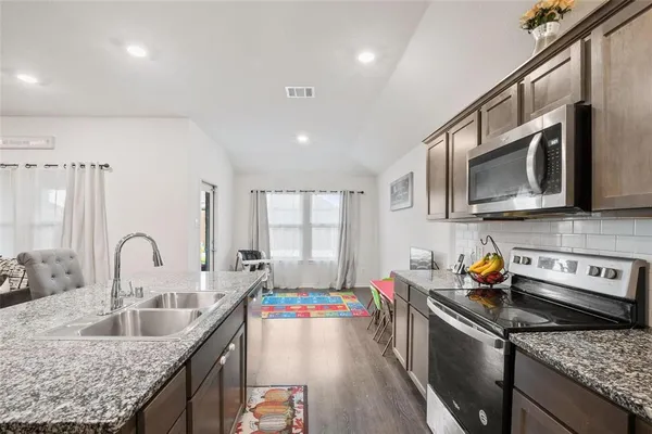 a kitchen with stainless steel appliances granite countertop a sink stove and refrigerator