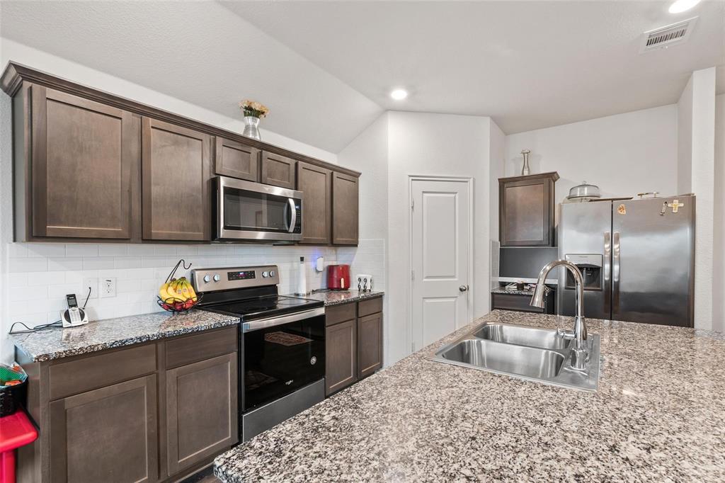 151 Seabiscuit Road Caddo Mills, TX 75135 - Photo 10 of 40 a kitchen with stainless steel appliances granite countertop a sink stove microwave and refrigerator