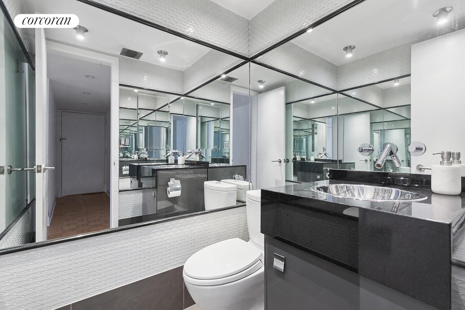 250 East 40th Street, Unit 17F Manhattan, NY 10016 - Photo 7 of 16 a bathroom with a granite countertop sink mirror vanity and toilet
