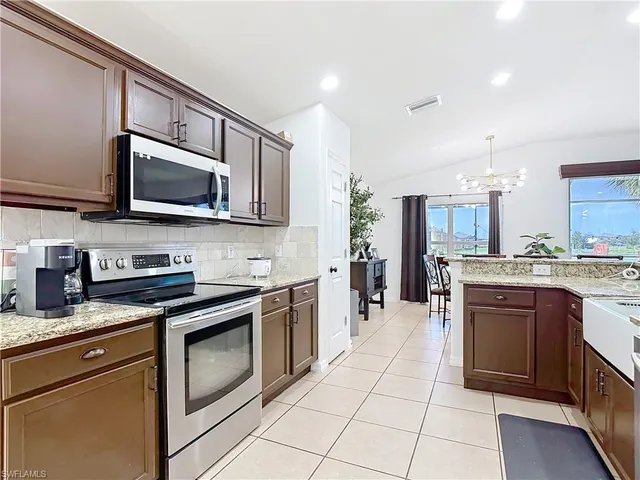 a kitchen with stainless steel appliances granite countertop a stove a sink and a microwave