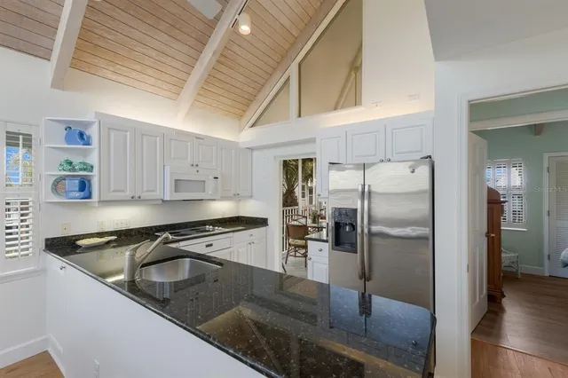 a kitchen with stainless steel appliances granite countertop a refrigerator a stove and a sink with wooden floors