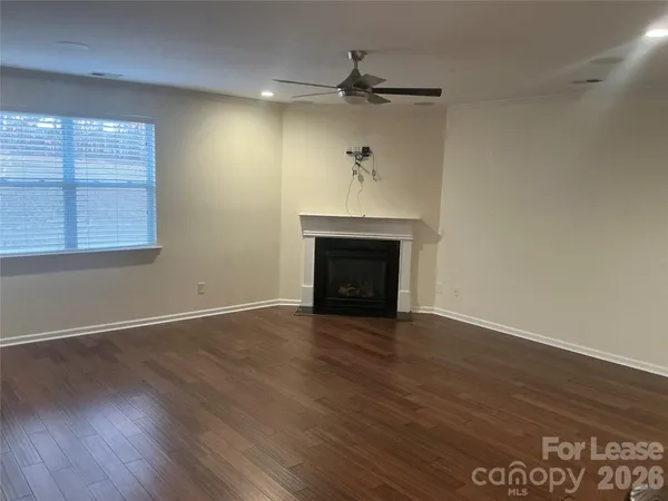 an empty room with wooden floor a ceiling fan and windows