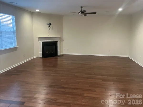 an empty room with wooden floor fireplace and windows