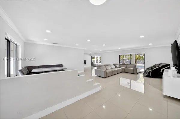 a living room with furniture a wooden floor and a kitchen