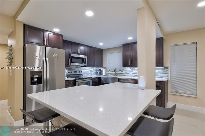3100 Riverside Drive, Unit 107 Coral Springs, FL 33065 - Photo 10 of 33 a large kitchen with kitchen island a large counter top space a sink stainless steel appliances and cabinets