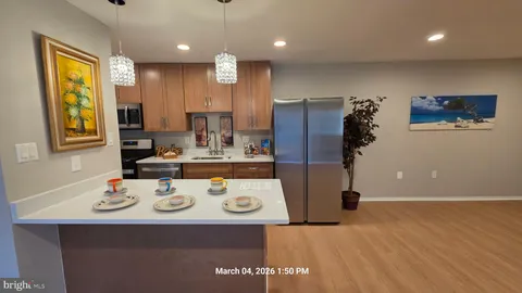 a kitchen with a refrigerator a stove a sink and a dining table with wooden floor