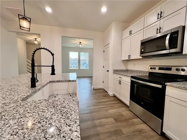 a kitchen with stainless steel appliances granite countertop a stove a sink and a microwave