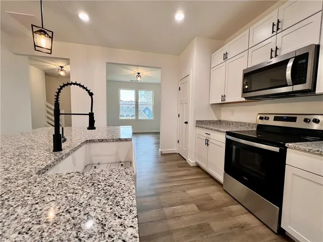 a kitchen with stainless steel appliances granite countertop a stove a sink and a microwave