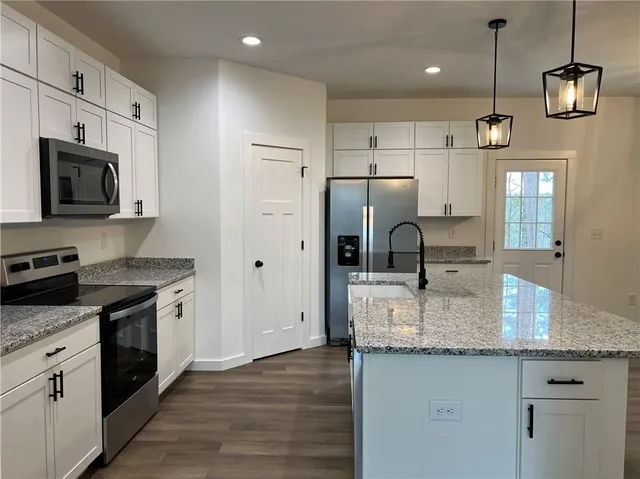 a kitchen with granite countertop a sink stove and refrigerator