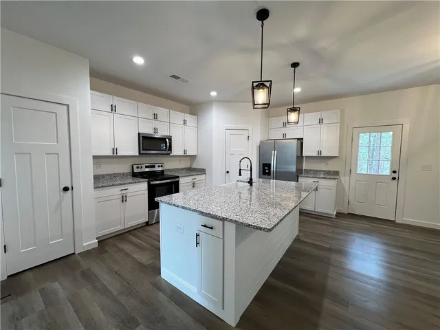 a kitchen with stainless steel appliances kitchen island granite countertop a stove a sink and a refrigerator