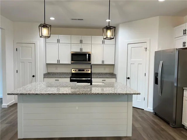 a large kitchen with stainless steel appliances a refrigerator and a stove