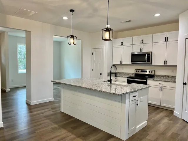 a kitchen with stainless steel appliances granite countertop a sink a stove a refrigerator and cabinets