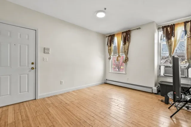 a view of an empty room with a window and wooden floor