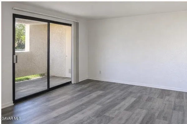 an empty room with wooden floor and two mirrors