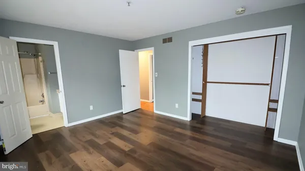 an empty room with wooden floor and a kitchen space