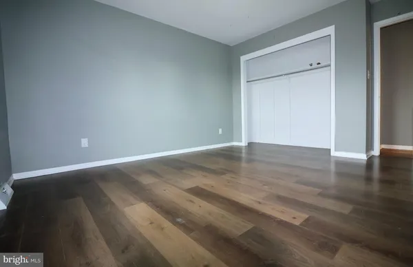 a view of an empty room with wooden floor and closet