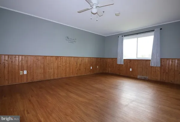 a view of an empty room with a window and wooden floor