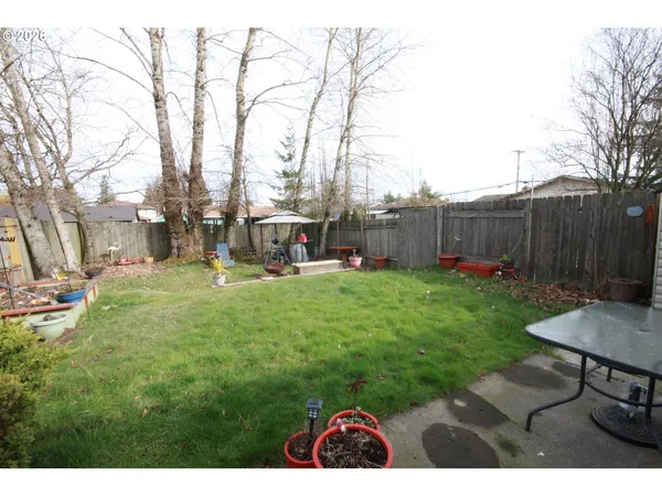 a view of backyard with table and chairs and wooden fence