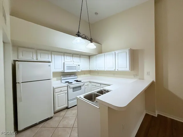 a kitchen with a sink a refrigerator and white cabinets