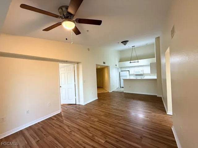 a view of empty room with wooden floor and fan