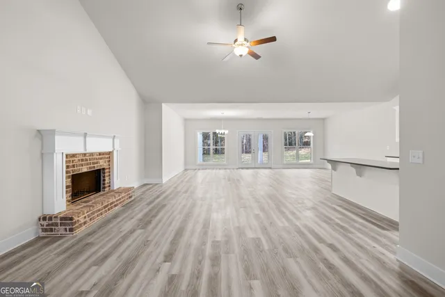 a view of an empty room with wooden floor fireplace and a window
