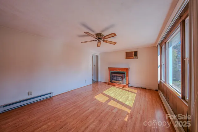 a view of an empty room with a window and wooden floor