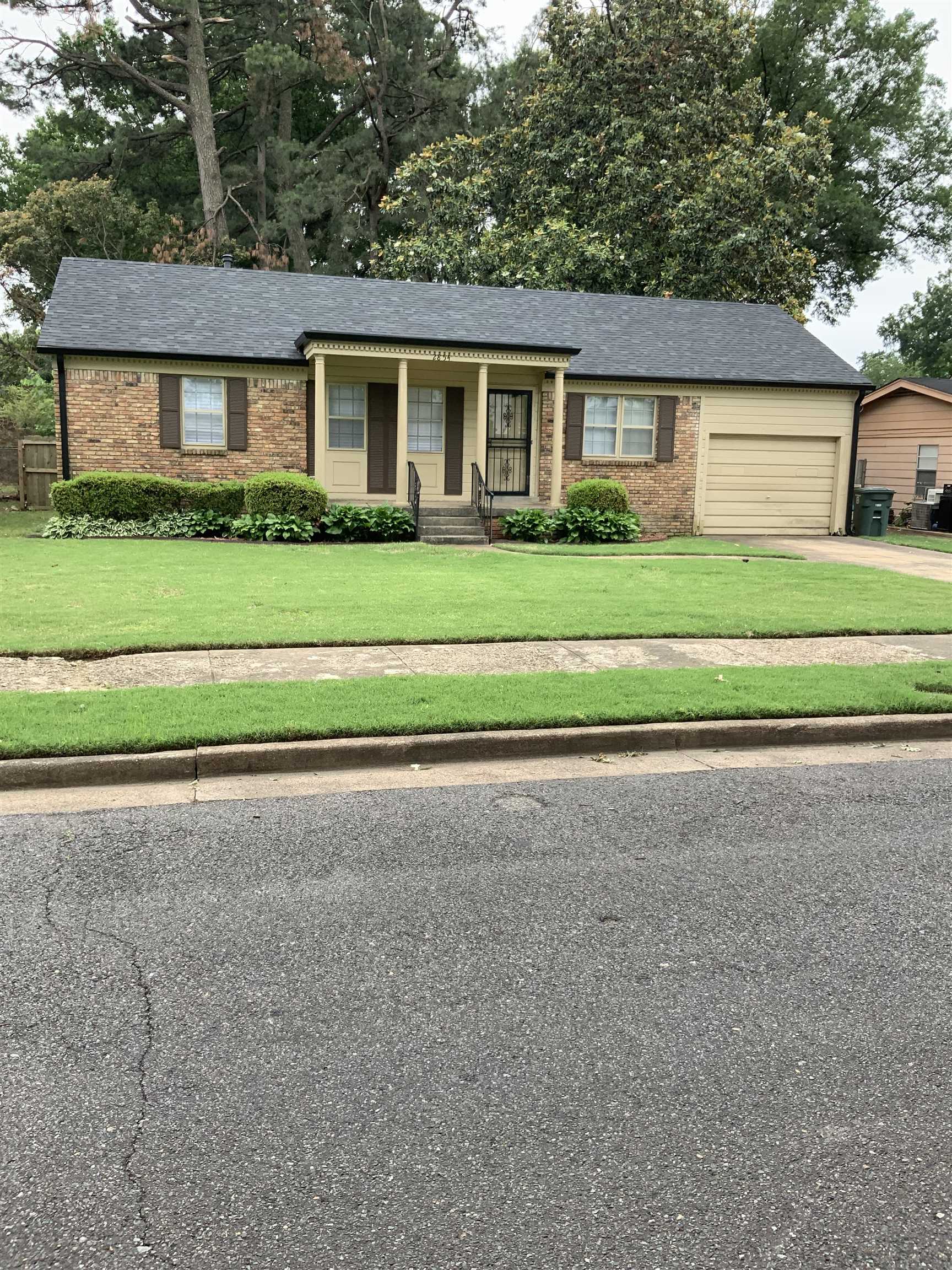 a front view of a house with a garden and trees