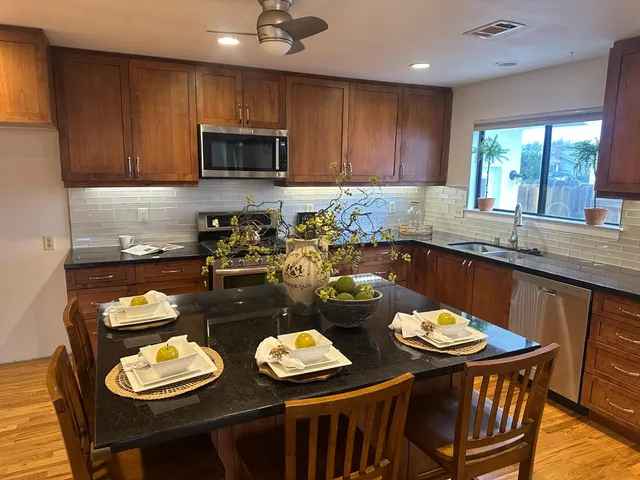 a kitchen with granite countertop a stove a sink a dining table and chairs