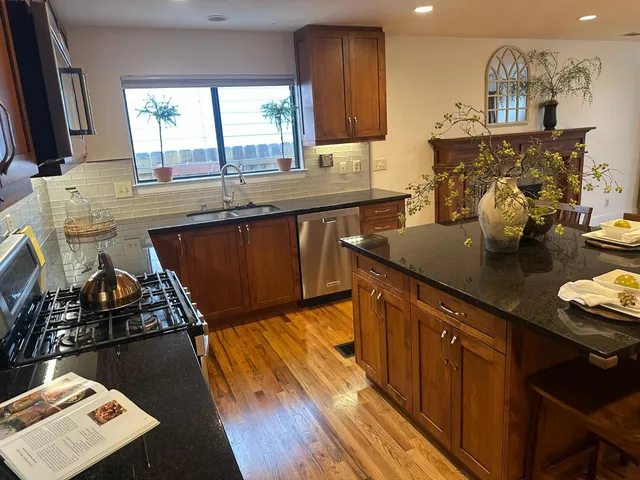 a kitchen with stainless steel appliances kitchen island granite countertop a stove a sink a dining table and chairs