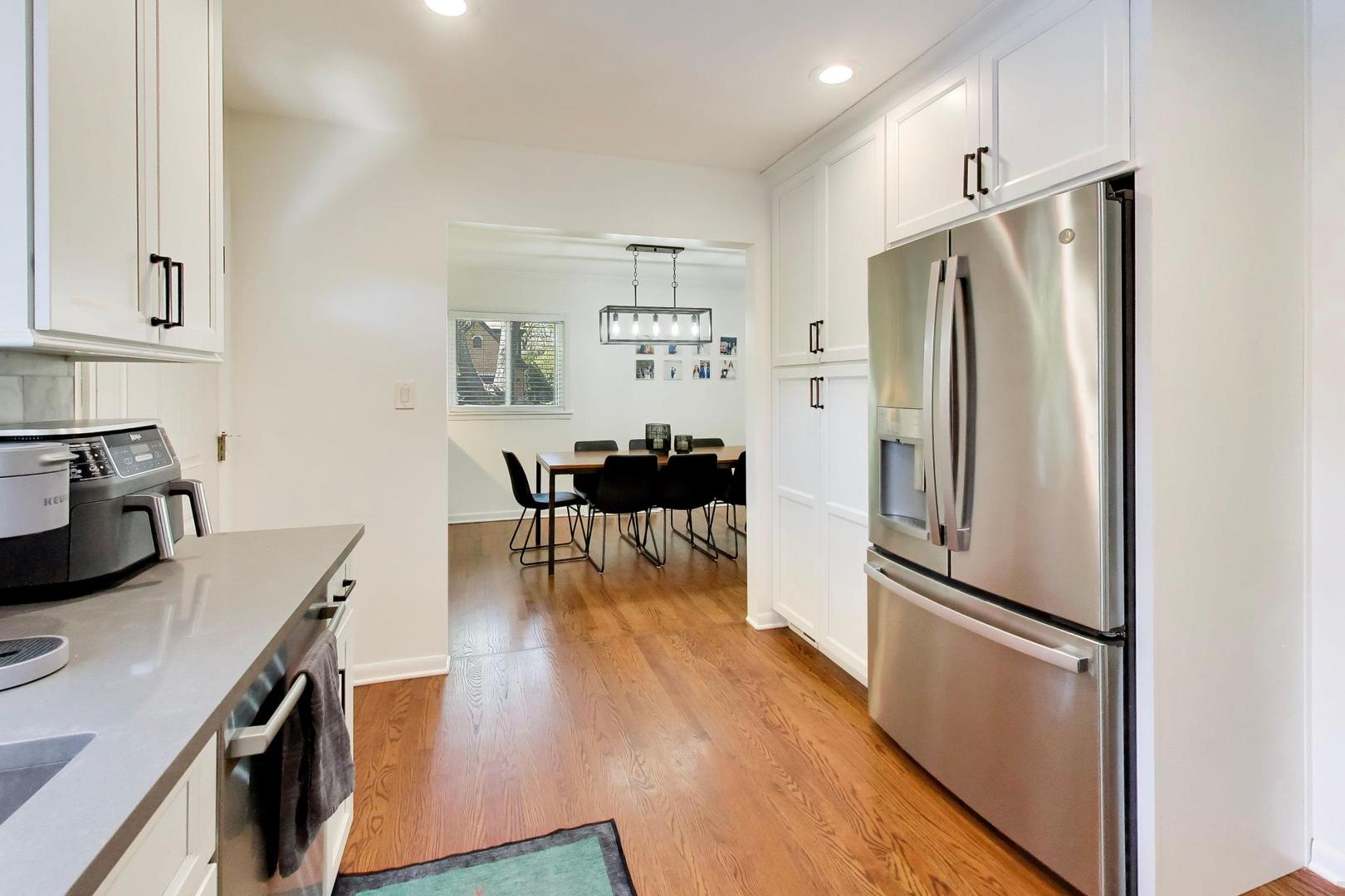 1153 Kenton Road Deerfield, IL 60015 - Photo 12 of 40 a kitchen with kitchen island a refrigerator a stove a sink and a dining table with wooden floor