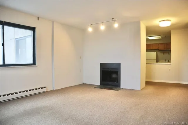 a view of an empty room with window and a kitchen