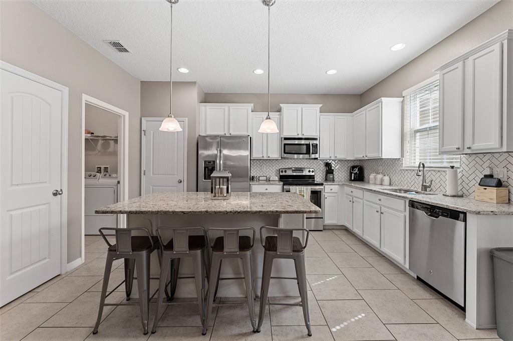 3523 Clay Brick Road St. Cloud, FL 34773 - Photo 17 of 62 a kitchen with kitchen island granite countertop a table chairs sink and cabinets