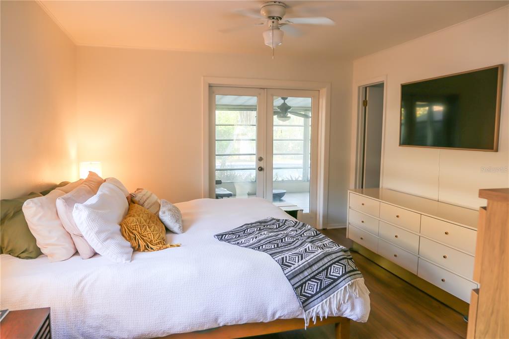 1810 Copper Kettle Lane Dunedin, FL 34698 - Photo 7 of 22 a bedroom with a large bed and a flat tv screen on dresser
