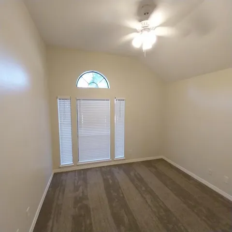 an empty room with a window and a fan