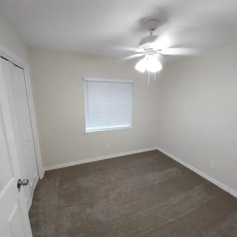 an empty room with windows and fan