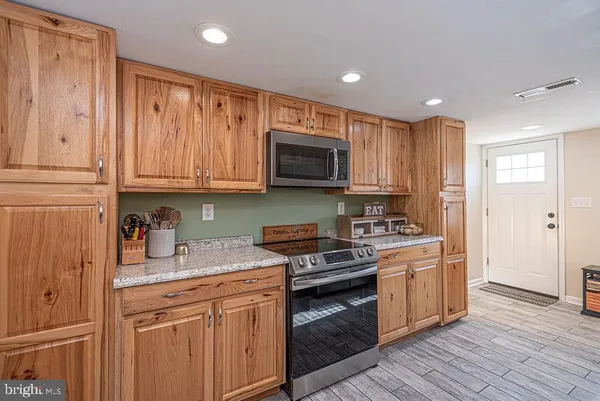 a kitchen with stainless steel appliances granite countertop a stove a sink and a microwave