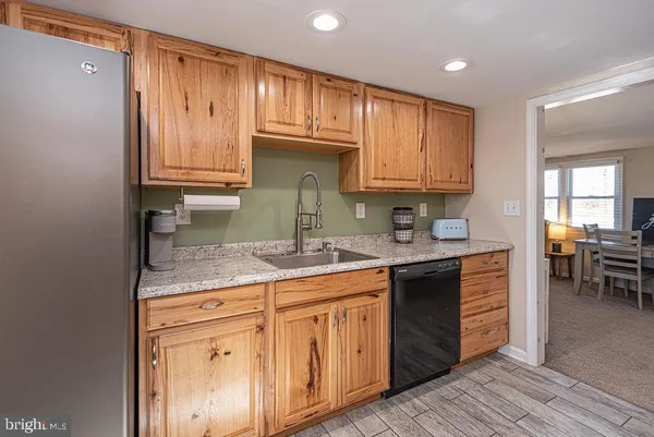 a kitchen with granite countertop wooden cabinets a sink and dishwasher