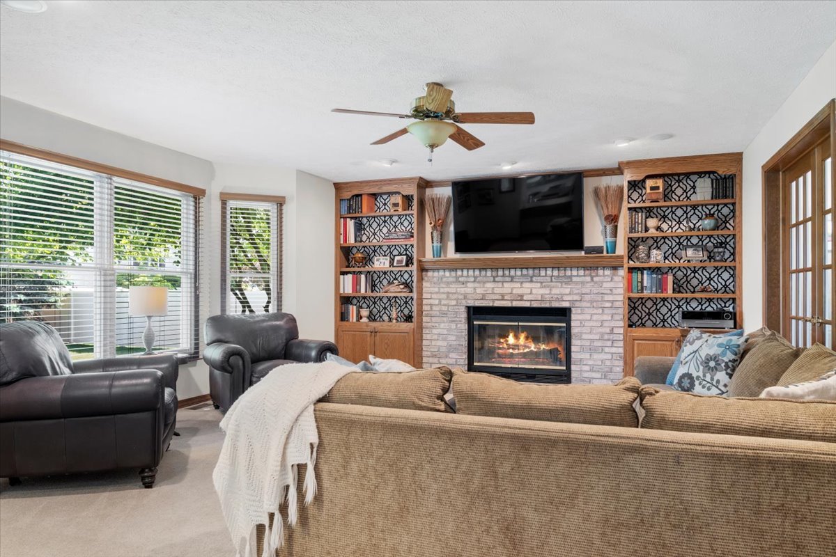 3215 Eagle Crest Road Bloomington, IL 61704 - Photo 6 of 35 a living room with furniture a flat screen tv and a fireplace