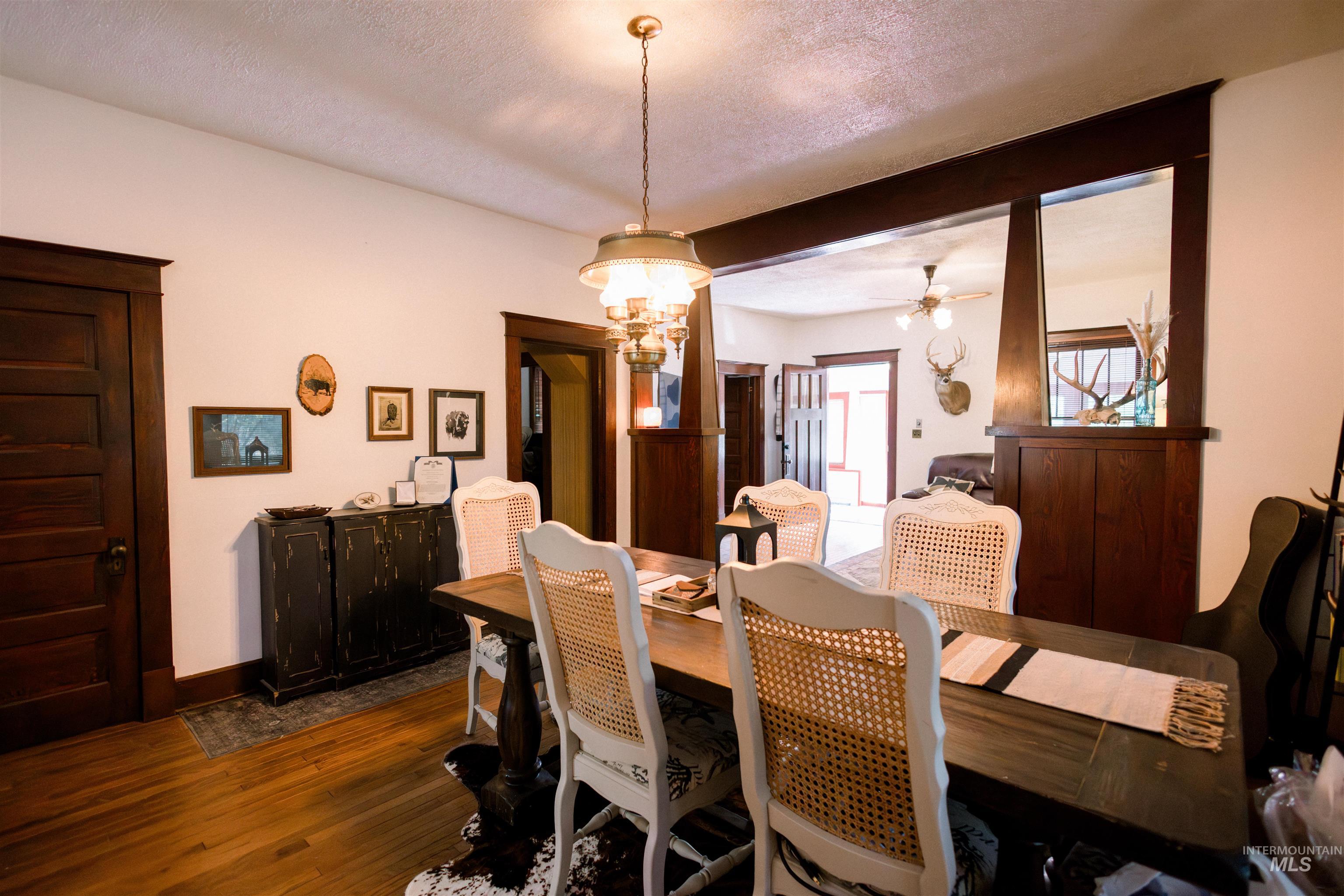 450 South 3rd E Street Mountain Home, ID 83647 - Photo 11 of 35 Dining space with dark wood finished floors, ceiling fan, a chandelier, and a textured ceiling