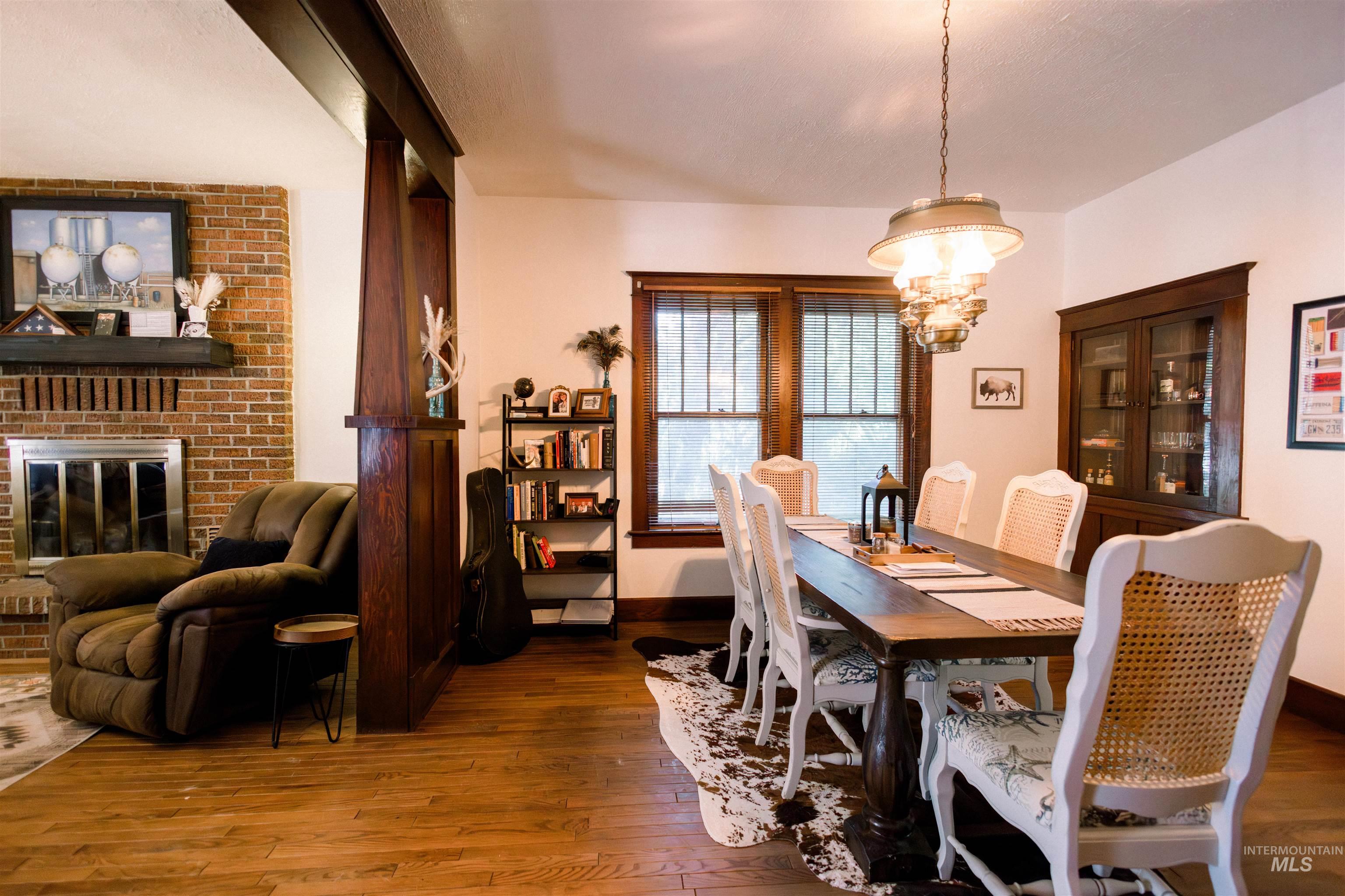 450 South 3rd E Street Mountain Home, ID 83647 - Photo 12 of 35 Dining room featuring wood-type flooring, a chandelier, and a brick fireplace