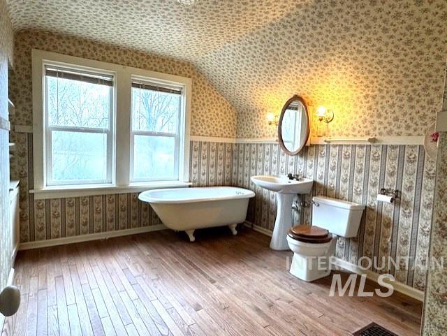 450 South 3rd E Street Mountain Home, ID 83647 - Photo 30 of 35 Bathroom featuring wallpapered walls, vaulted ceiling, wood-type flooring, and a freestanding tub