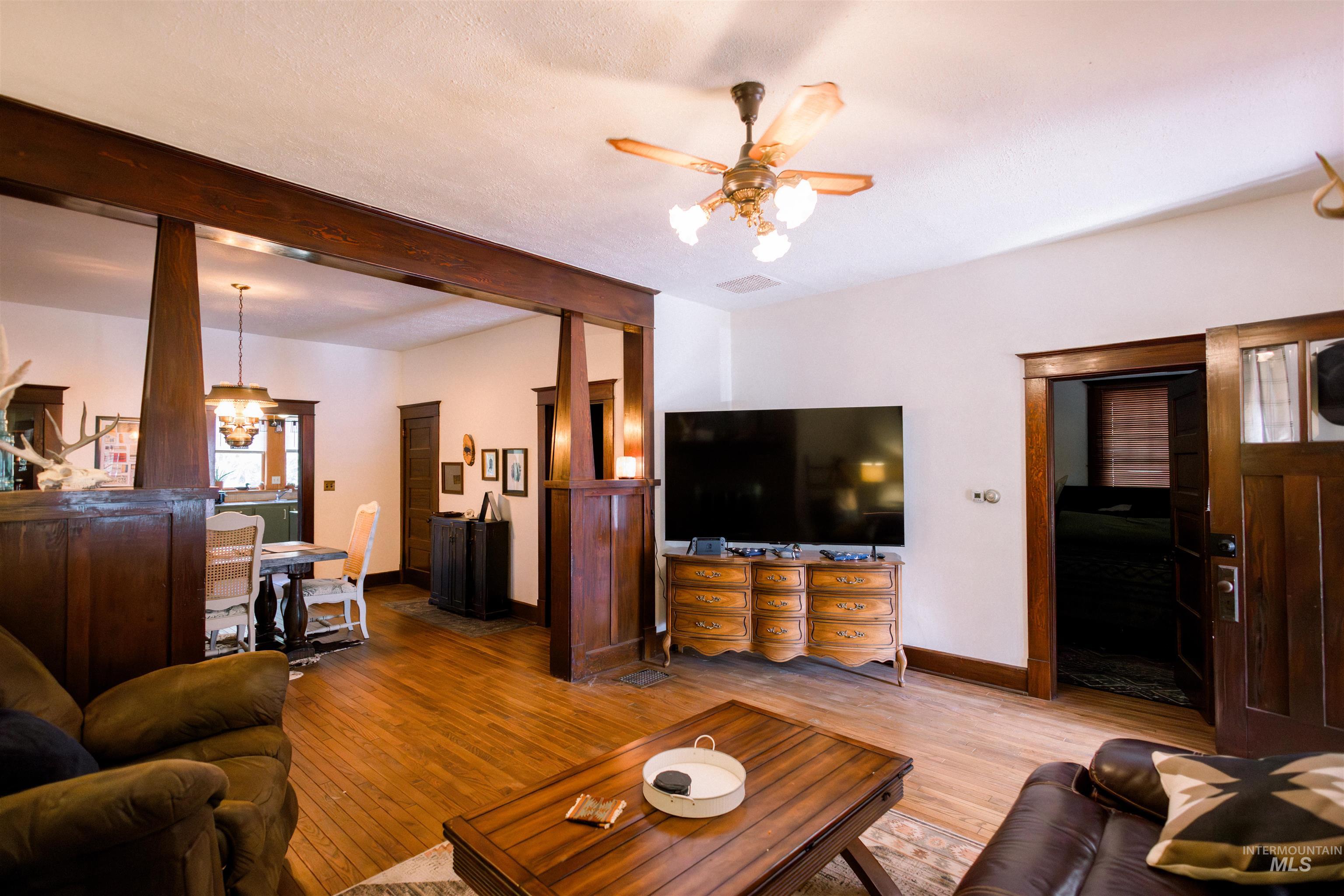 450 South 3rd E Street Mountain Home, ID 83647 - Photo 5 of 35 Living area featuring ceiling fan, wood finished floors, beam ceiling, and a chandelier