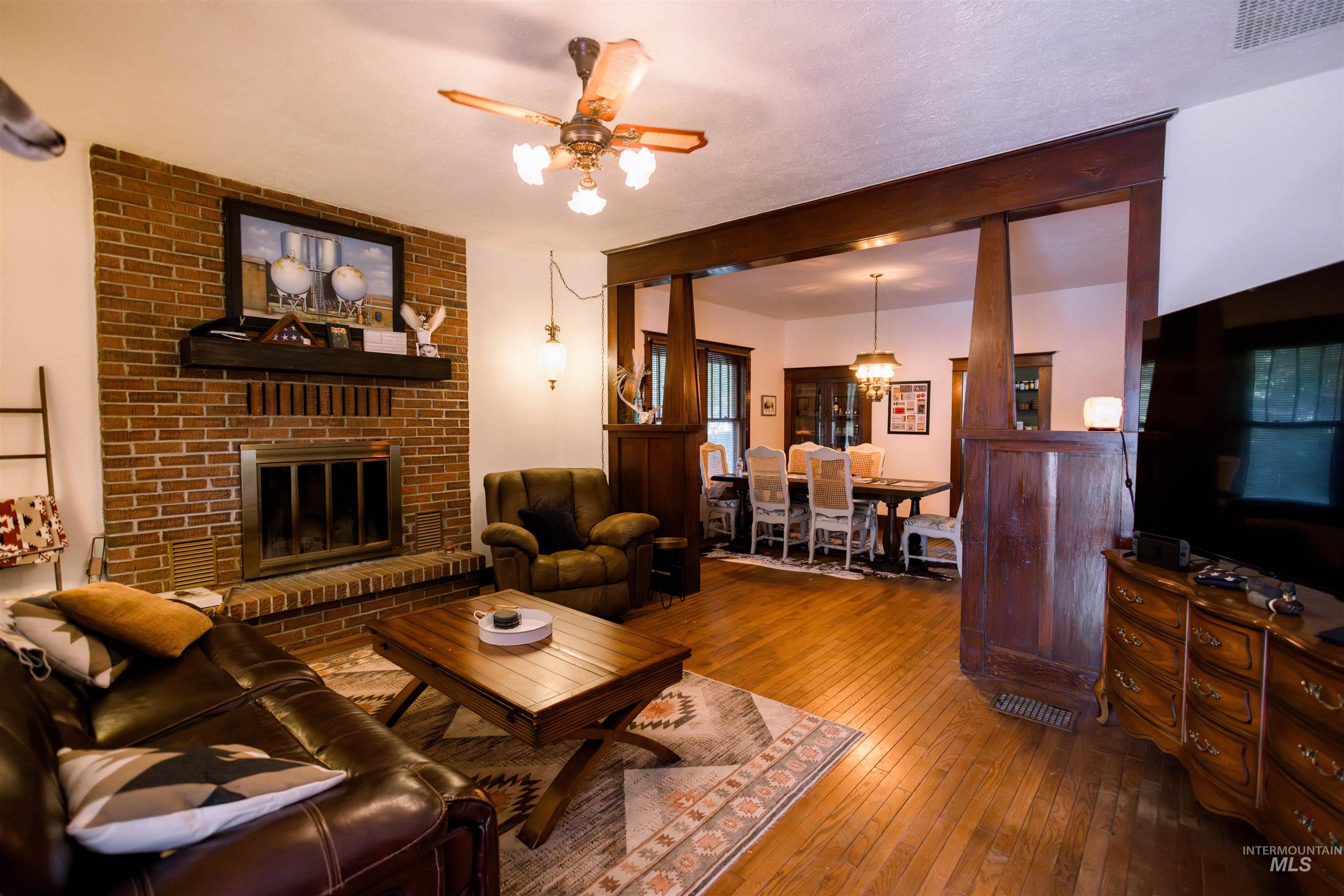 450 South 3rd E Street Mountain Home, ID 83647 - Photo 6 of 35 Living room with wood-type flooring, ceiling fan, a brick fireplace, and a chandelier