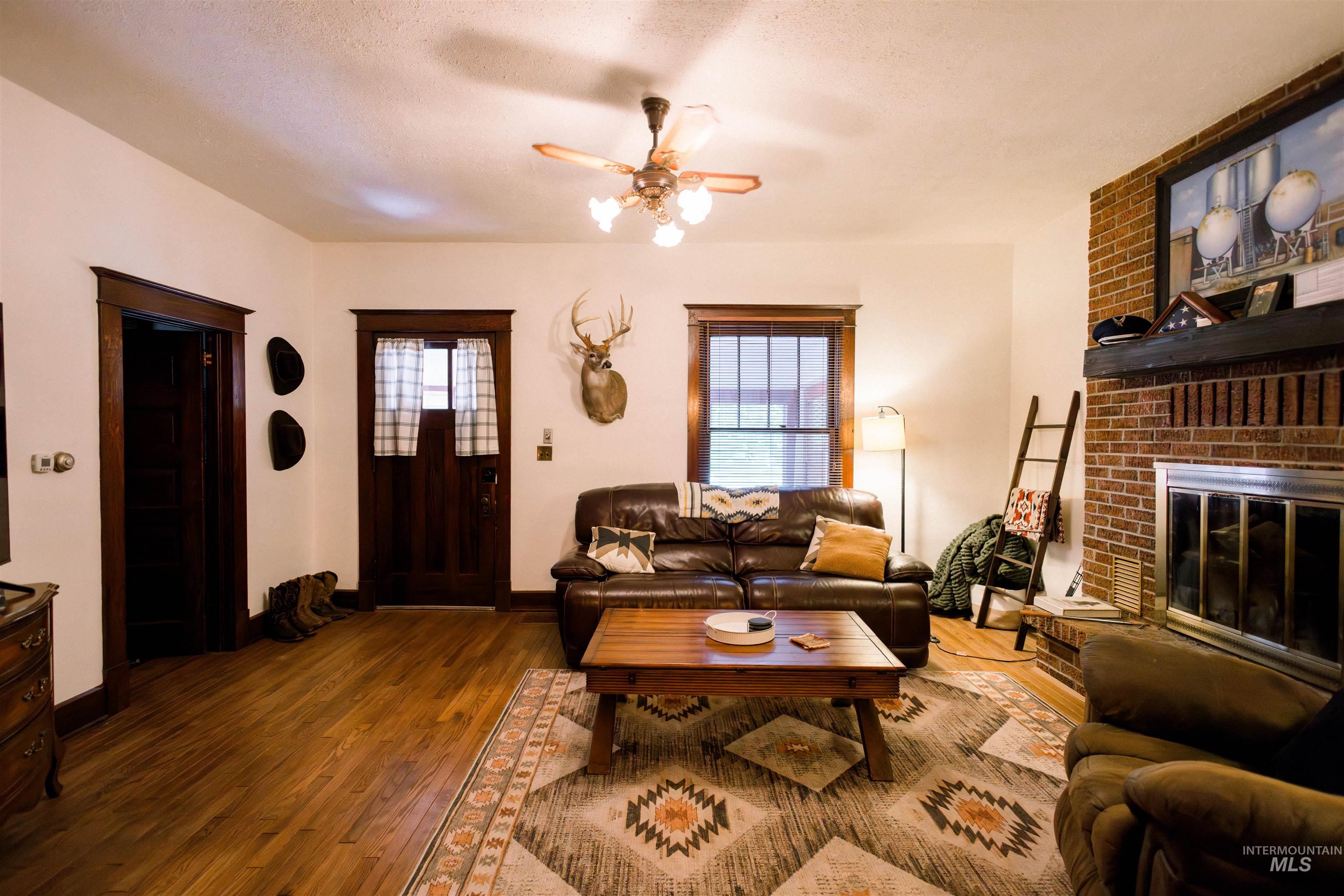 450 South 3rd E Street Mountain Home, ID 83647 - Photo 7 of 35 Living room with a ceiling fan, wood finished floors, a brick fireplace, and a textured ceiling