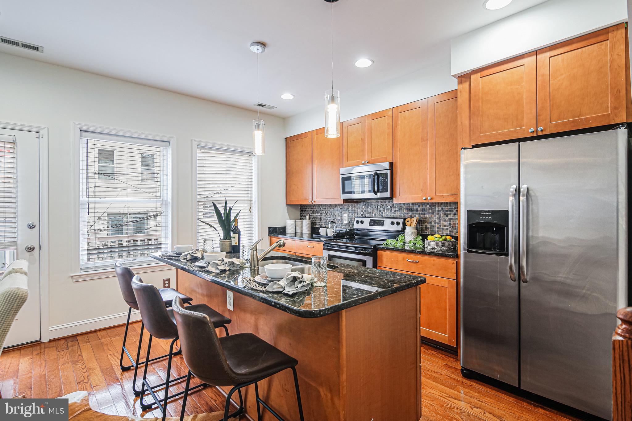 3418 Gunther Way Baltimore, MD 21224 - Photo 12 of 57 a kitchen with stainless steel appliances granite countertop a stove a refrigerator a kitchen island a table and chairs