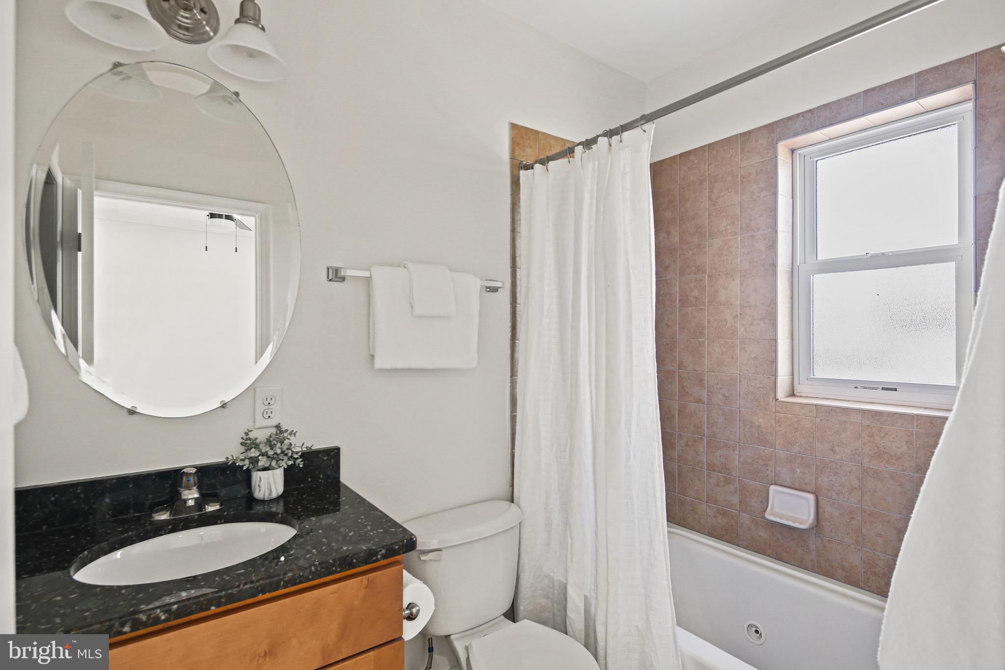 3418 Gunther Way Baltimore, MD 21224 - Photo 31 of 57 a bathroom with a granite countertop sink toilet a mirror a vanity and shower