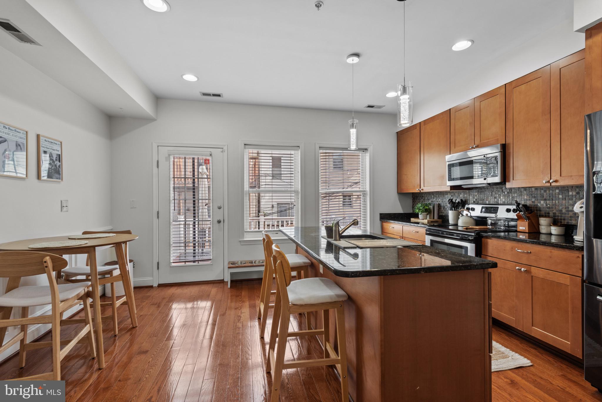 3418 Gunther Way Baltimore, MD 21224 - Photo 9 of 57 a kitchen with stainless steel appliances granite countertop a refrigerator a stove top oven a sink dishwasher and white cabinets with wooden floor